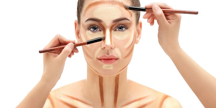 A woman having contouring make up applied to her face and chest